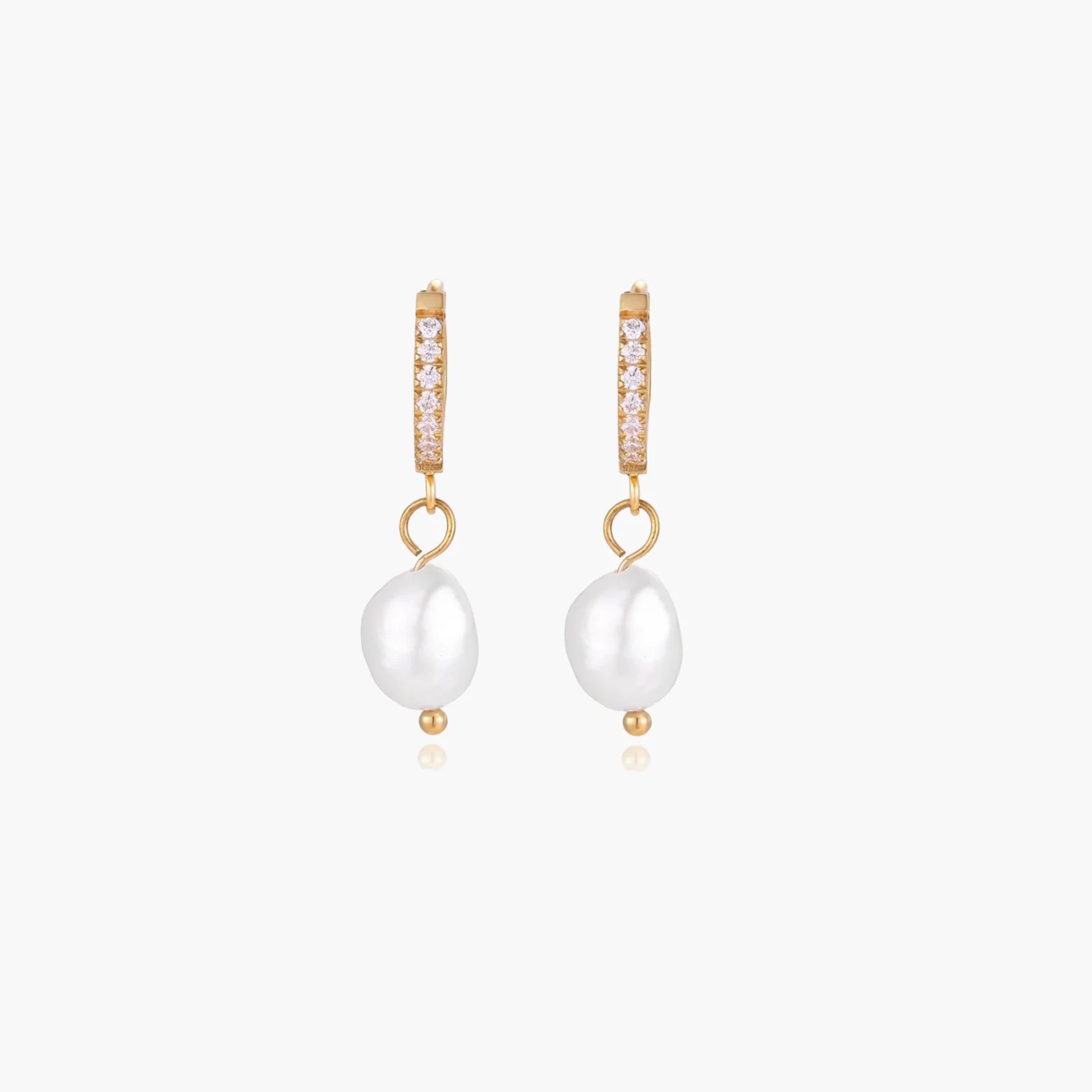 Gold huggie hoop earrings with pavé crystals and white freshwater pearl drops on cream background